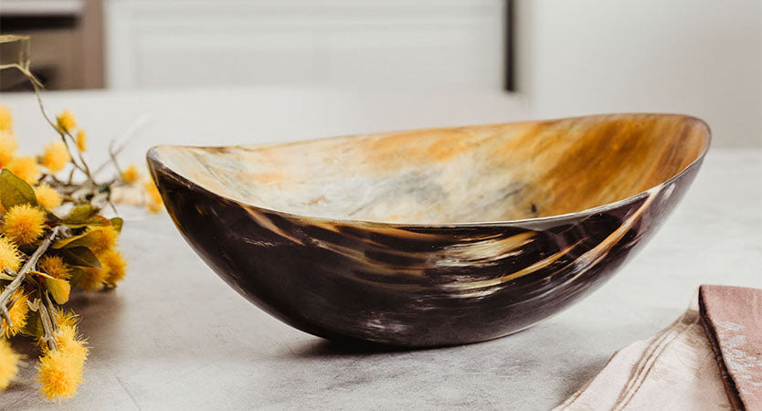 Two wooden candles sticks in the corner with shadows. One candle is burning and one candle has just been blown out. 